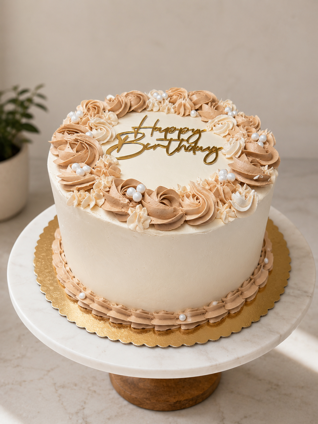Ivory birthday cake with beige piped rosettes, white pearls, and a gold Happy Birthday topper